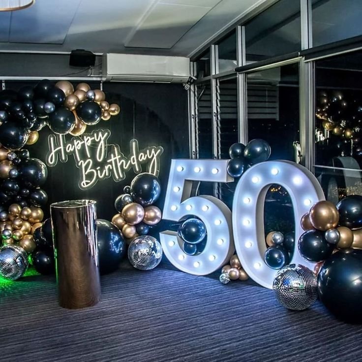 Letras luminosas del 50 con arco de globos negros y dorados