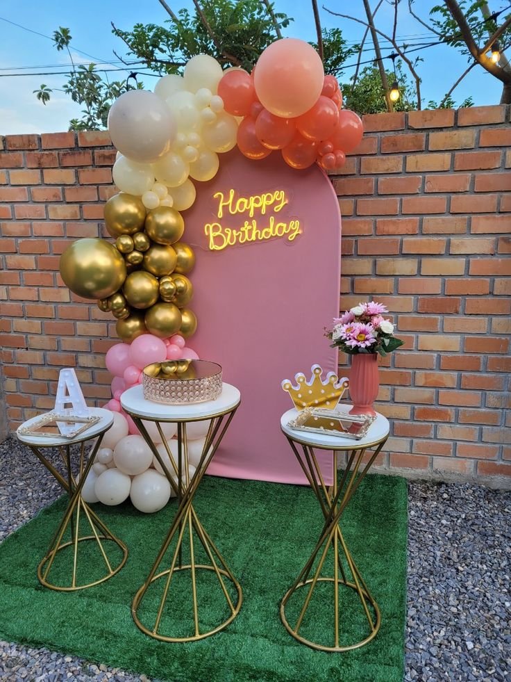 Fondo rosa con arco de globos en tonos coral y dorado