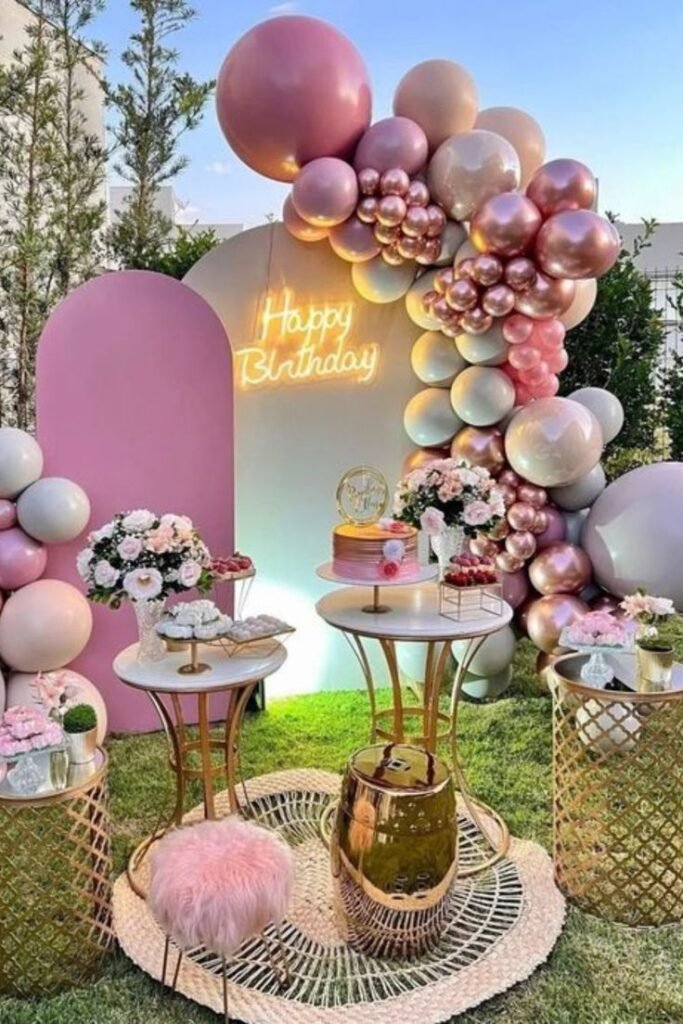 Paneles rosas con globos y mesa de postres al aire libre