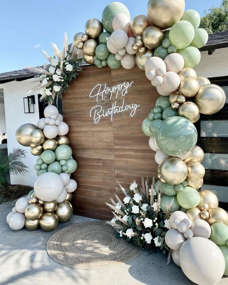 Arco de globos verde salvia y dorados con panel de madera