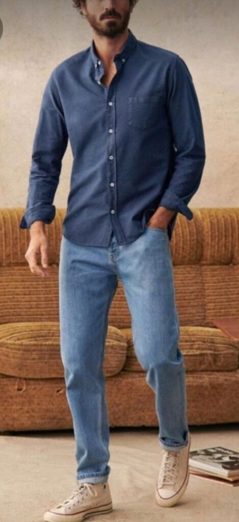 Camisa azul marino con jeans claros y tenis beige