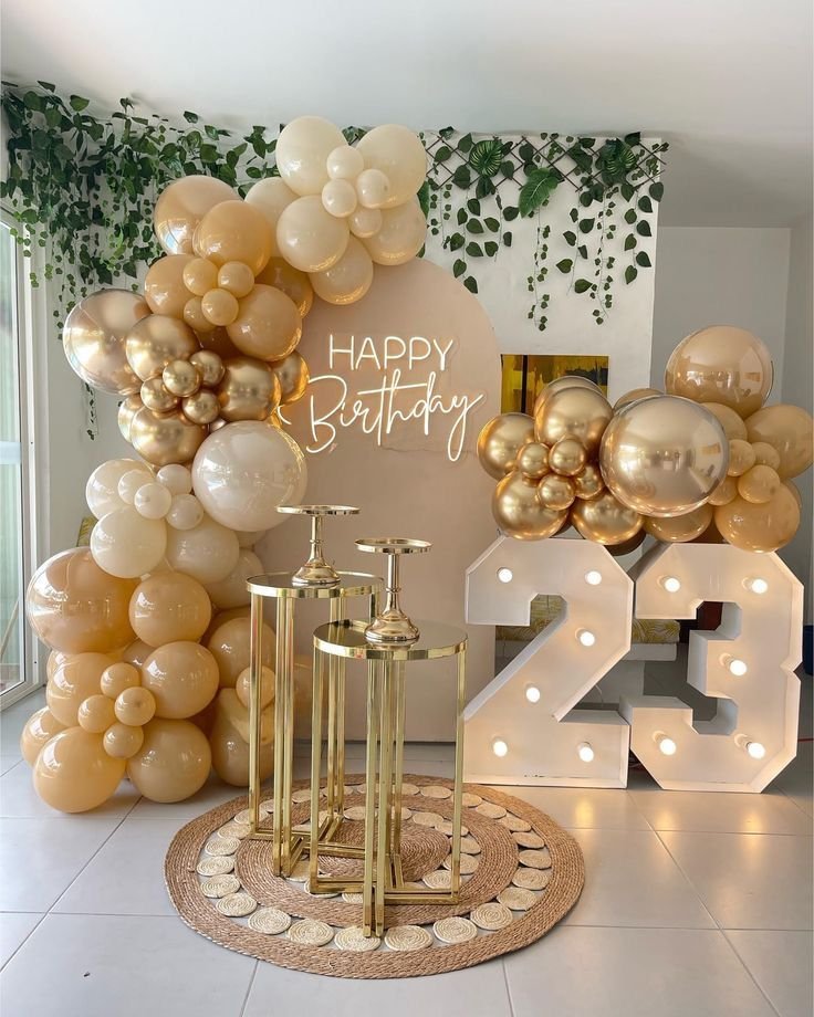 Arco de globos crema y dorados con el número 23 iluminado