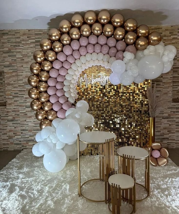 Arco de globos rosa empolvado y dorado sobre panel de lentejuelas