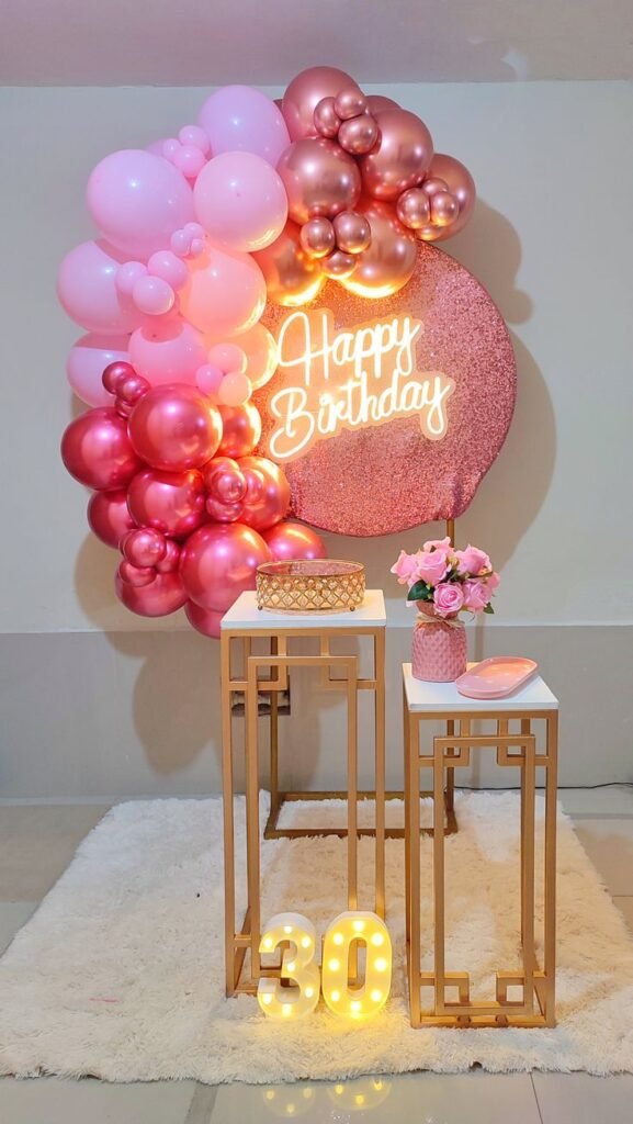 Fondo rosa con arco de globos y letras luminosas del número 30