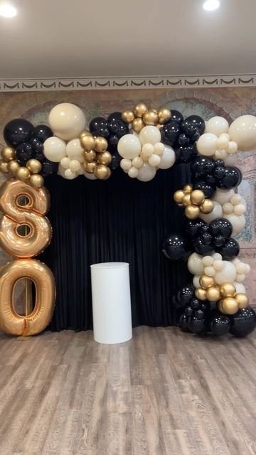 Arco de globos beige y negros con el número 80 dorado