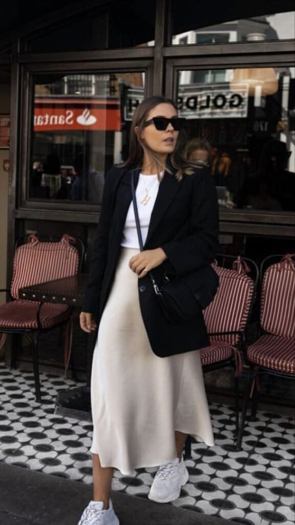 Blazer negro con falda midi crema y tenis