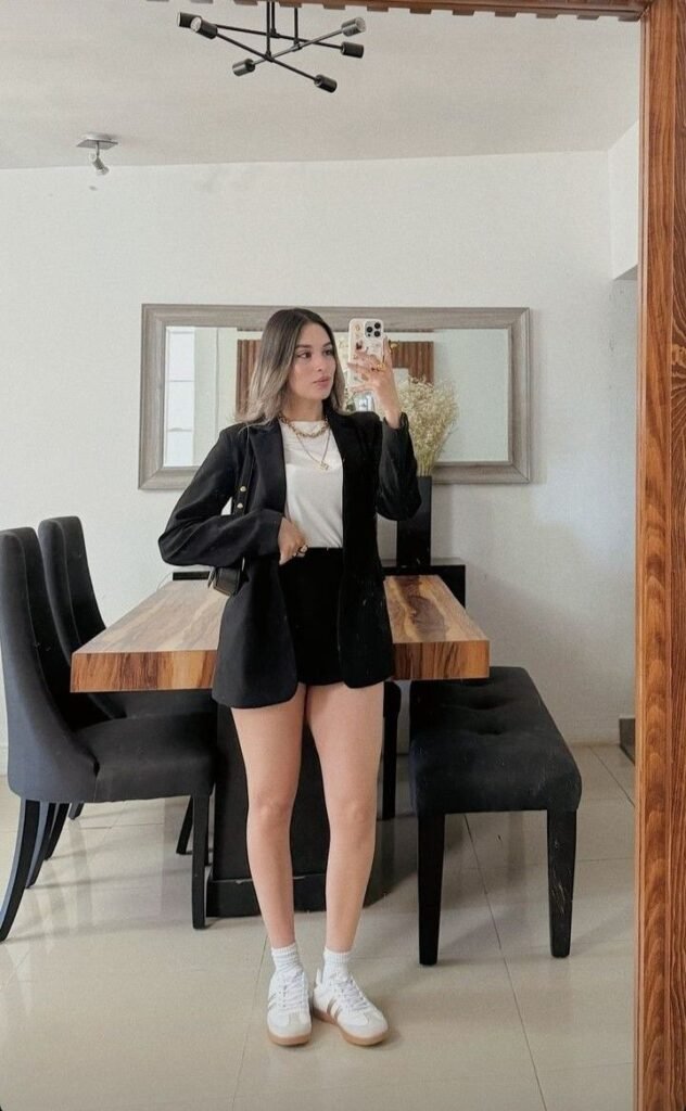 Chaqueta de cuero negra con shorts negros y tenis blancos