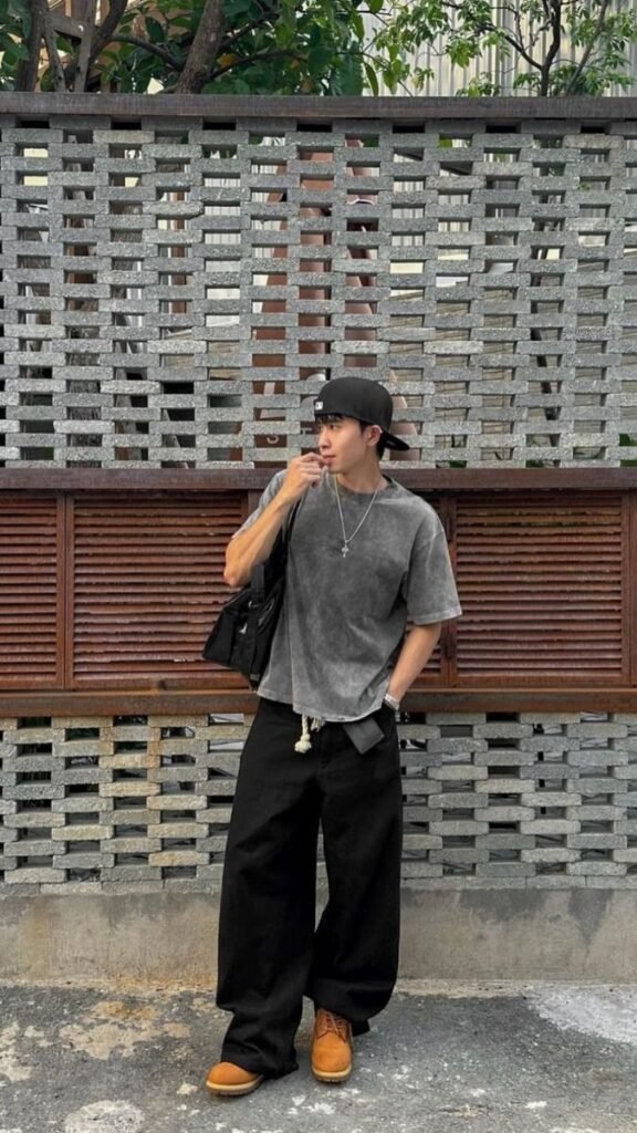 Camiseta gris con jeans anchos negros y gorra