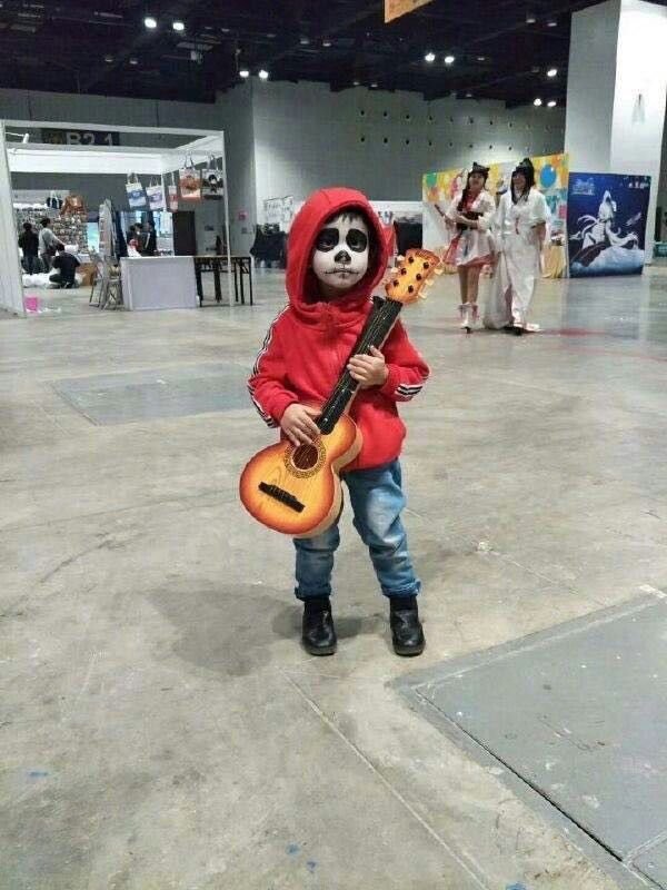 Niño disfrazado de músico con guitarra y maquillaje de calavera
