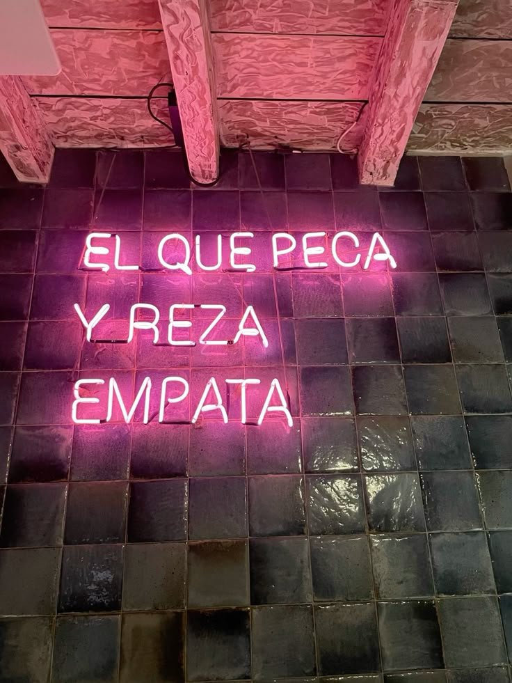 Letrero de neón rosa con una frase en una pared de azulejos