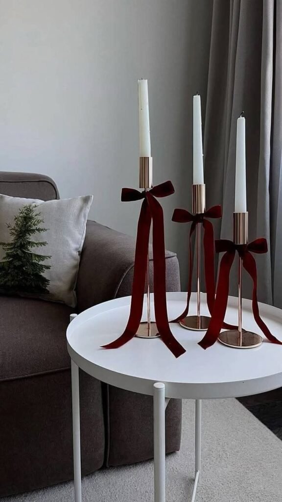 Velas con lazos de terciopelo burdeos sobre mesa auxiliar