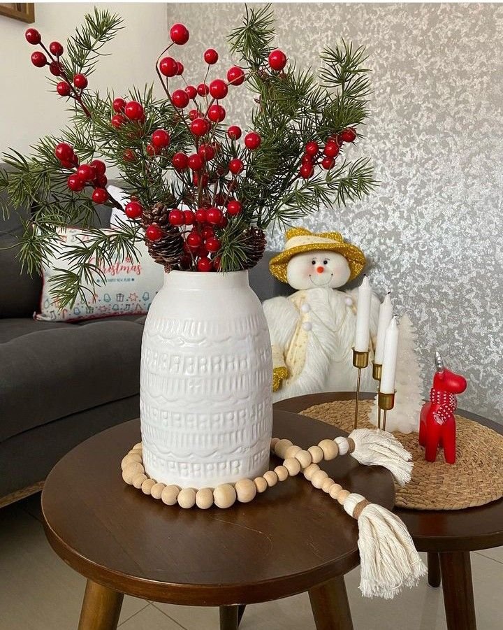 Jarrón blanco con bayas rojas y muñeco de nieve de madera